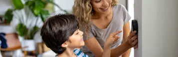 Mother and son adjusting thermostat 